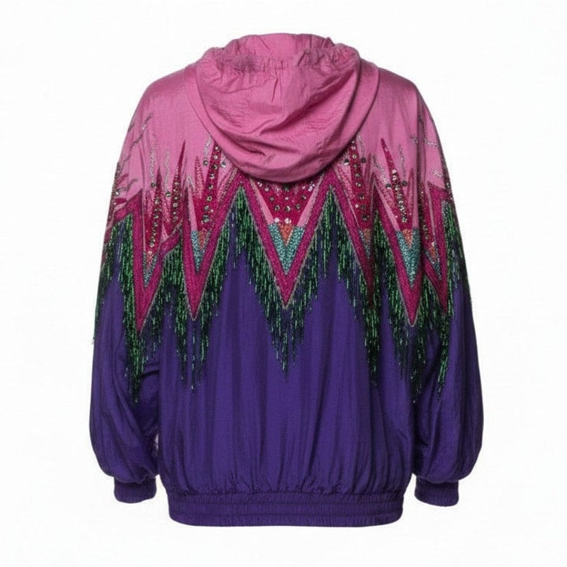 A hooded windbreaker jacket shown from the back, featuring a vibrant magenta-to-purple gradient with a large geometric chevron pattern in pink, green, and purple adorned with sequins and fringe.